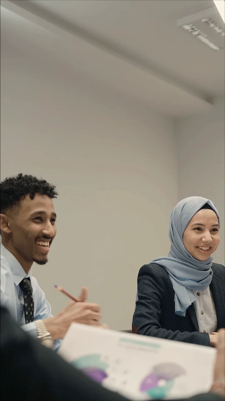 Two candidates smile across the table from their interviewer, an interview going well.