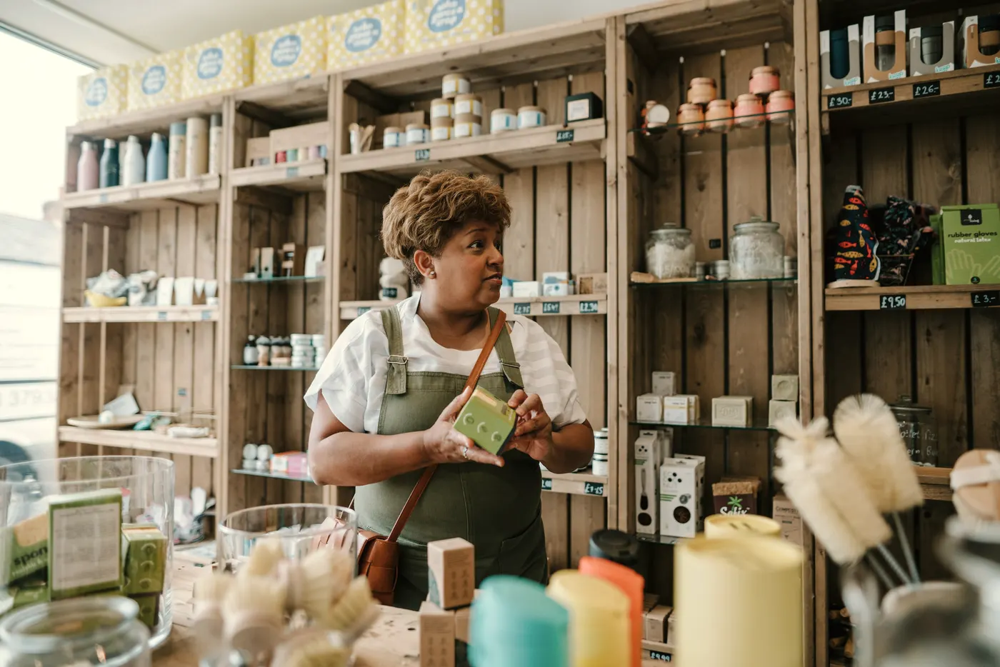 A shop assistant among wooden shelves of products.
