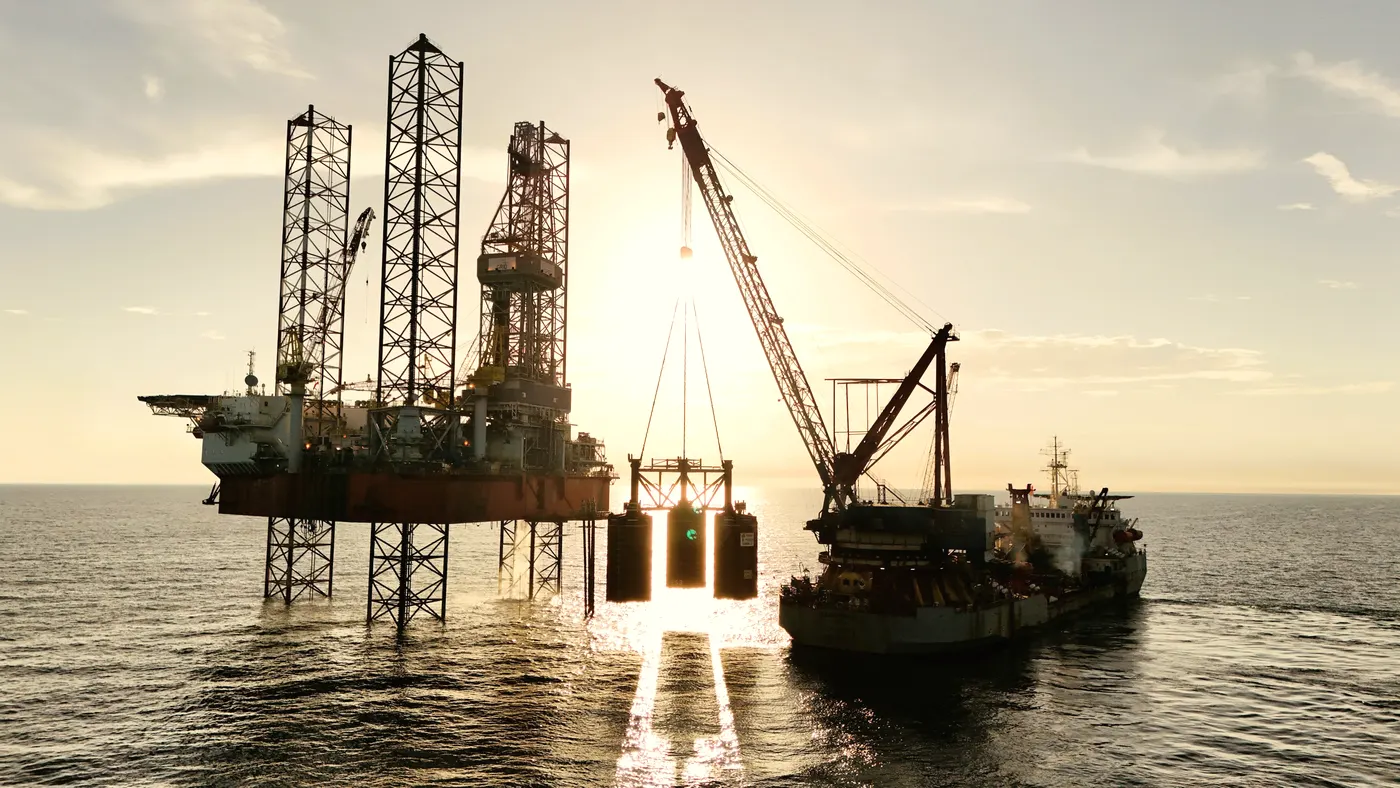 An offshore platform and supply vessel at golden hour.